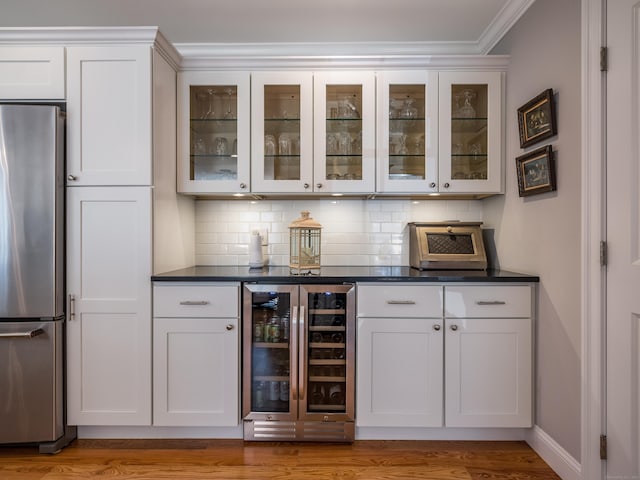bar with wine cooler, ornamental molding, freestanding refrigerator, and backsplash