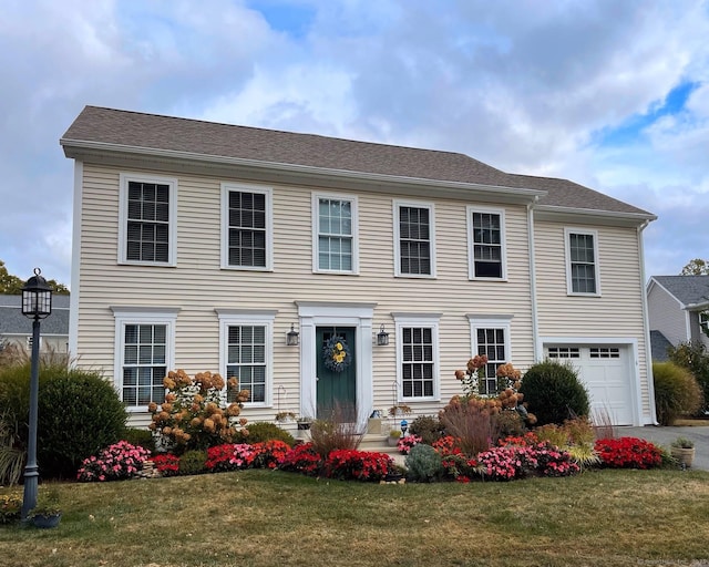 colonial-style house featuring a garage and a front yard