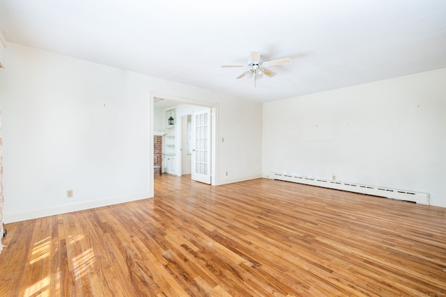 spare room with light wood-type flooring, baseboards, ceiling fan, and a baseboard heating unit