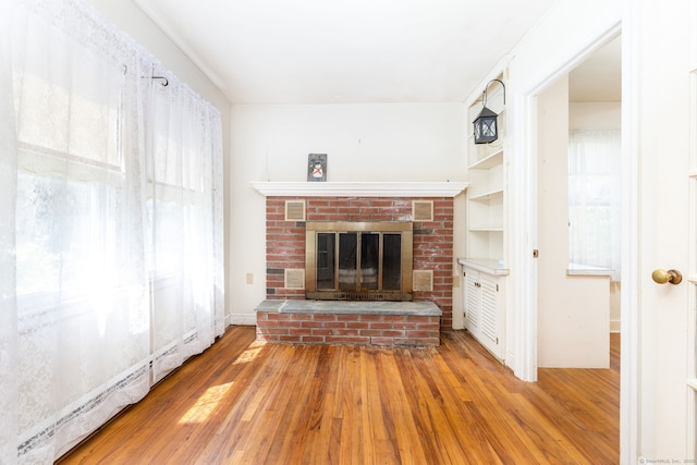unfurnished living room with a brick fireplace and wood finished floors