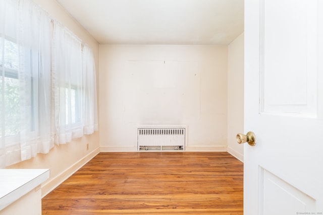 empty room with light wood-style flooring, radiator, and a healthy amount of sunlight
