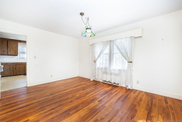 unfurnished room with light wood-style floors, baseboards, and radiator heating unit