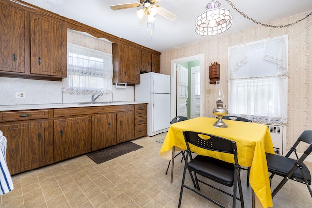 kitchen featuring ceiling fan, light countertops, freestanding refrigerator, light floors, and wallpapered walls