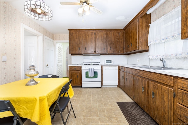 kitchen with a sink, light countertops, wallpapered walls, and white appliances