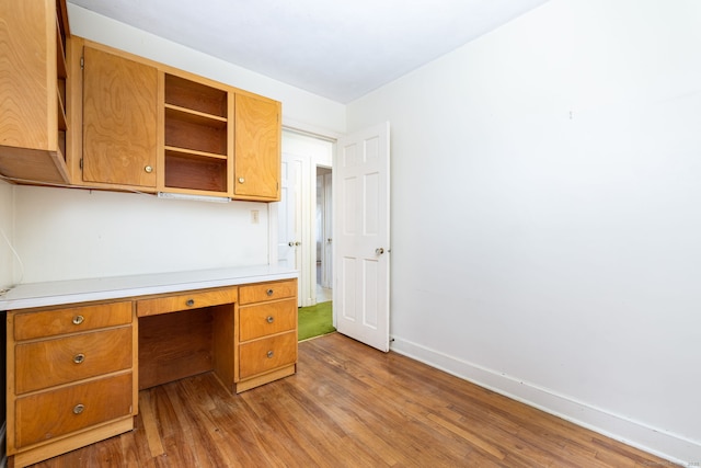 unfurnished office with baseboards and light wood-style flooring