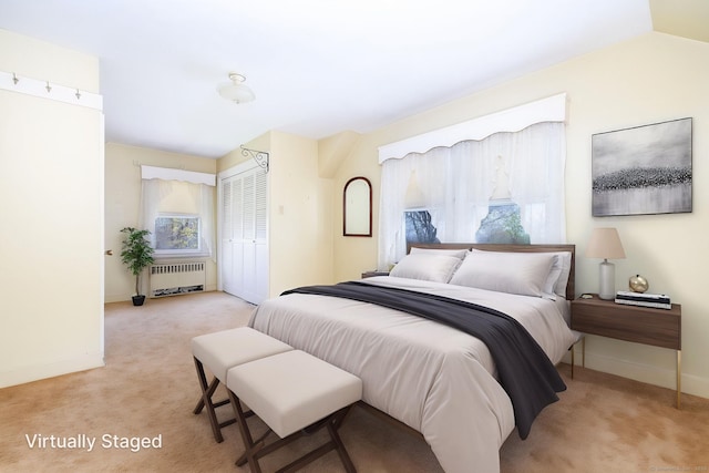 bedroom with radiator heating unit, baseboards, light carpet, and a closet