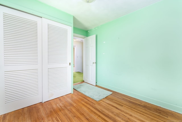 unfurnished bedroom featuring a closet, light wood finished floors, and baseboards