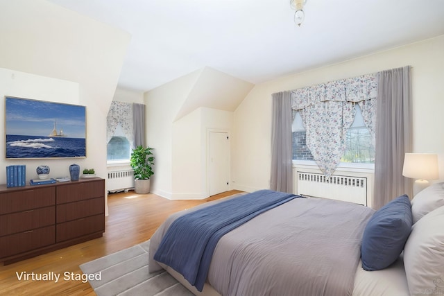 bedroom with wood finished floors, baseboards, and radiator heating unit