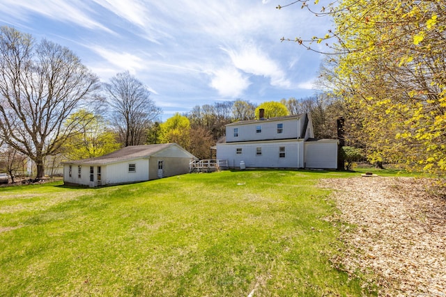 rear view of property with a lawn and an outbuilding