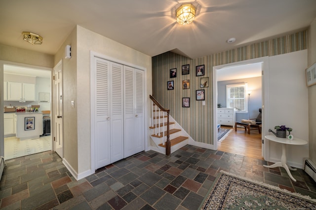 foyer with stairway, baseboards, stone tile floors, and wallpapered walls