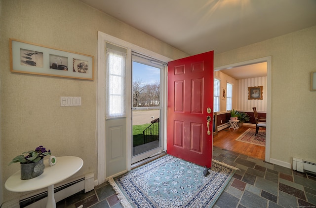 foyer entrance featuring a baseboard heating unit, stone tile floors, and baseboards