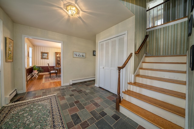 foyer featuring stairway, stone finish flooring, baseboards, a baseboard radiator, and baseboard heating