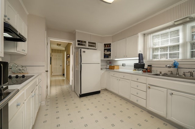 kitchen with a sink, freestanding refrigerator, open shelves, light floors, and under cabinet range hood