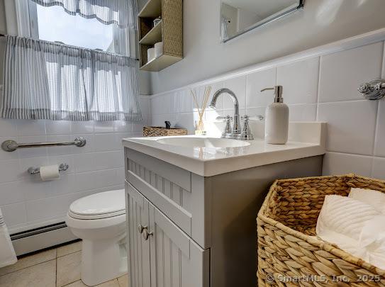 67 Stuart St, Newington, CT 06111 - bathroom with baseboard heating, toilet, tile patterned floors, vanity, and tile walls