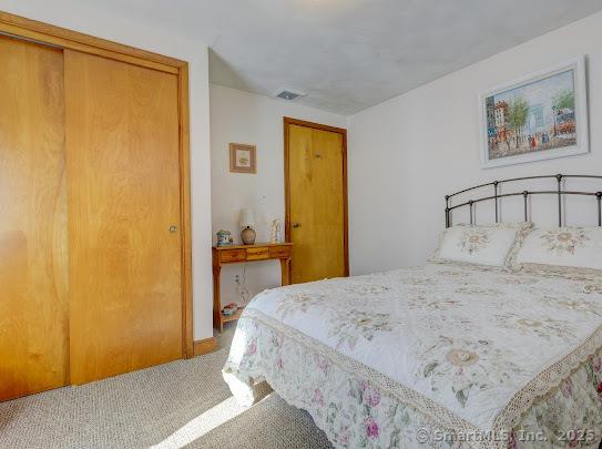carpeted bedroom featuring a closet and visible vents