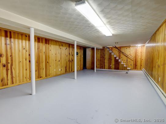 67 Stuart St, Newington, CT 06111 - finished below grade area featuring a baseboard radiator, stairs, and wood walls
