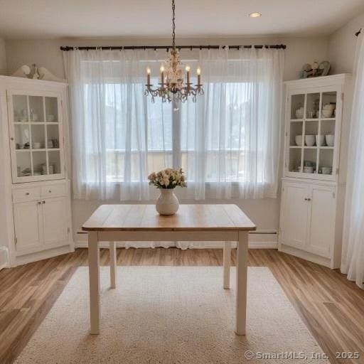 67 Stuart St, Newington, CT 06111 - dining room with light wood-type flooring, a chandelier, and a baseboard heating unit