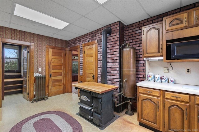 289 Gulf St, Milford, CT 06460 - office area with a paneled ceiling, brick wall, a wood stove, radiator, and light floors