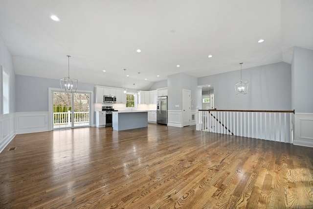 01 Sunrise Rd, Danbury, CT 06811 - unfurnished living room featuring a chandelier, vaulted ceiling, a decorative wall, dark wood-style floors, and a wainscoted wall