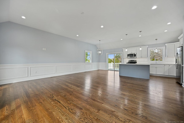 01 Sunrise Rd, Danbury, CT 06811 - unfurnished living room with recessed lighting, a chandelier, vaulted ceiling, dark wood-type flooring, and a wainscoted wall