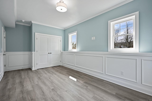 01 Sunrise Rd, Danbury, CT 06811 - unfurnished dining area with a wainscoted wall, ornamental molding, a decorative wall, and wood finished floors