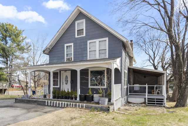 view of front facade featuring a chimney and covered porch