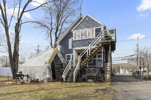 view of front of house featuring an outdoor structure, a detached carport, stairway, driveway, and fence