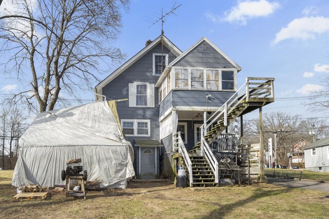 view of front of house with stairs, a deck, a chimney, and an outbuilding