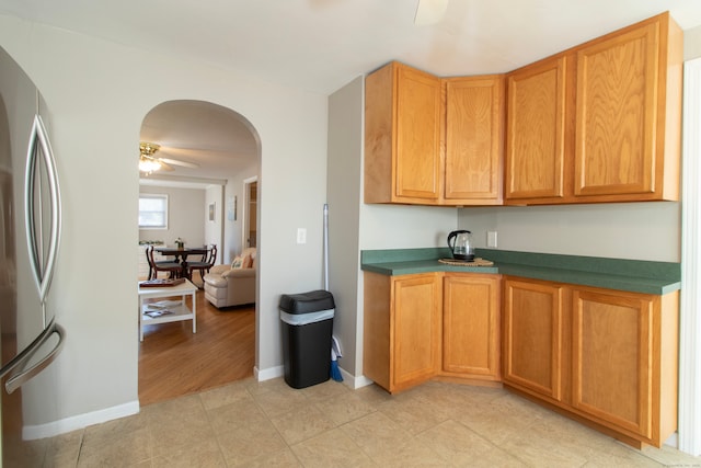 102 Broadway, Milford, CT 06460 - kitchen featuring freestanding refrigerator, dark countertops, baseboards, arched walkways, and a ceiling fan