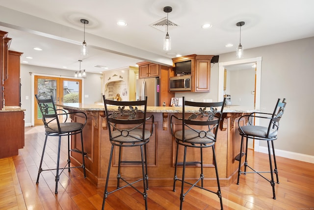 kitchen with appliances with stainless steel finishes, baseboards, light stone countertops, and light wood finished floors