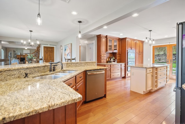 kitchen featuring double oven, light wood-style floors, a sink, dishwasher, and a notable chandelier