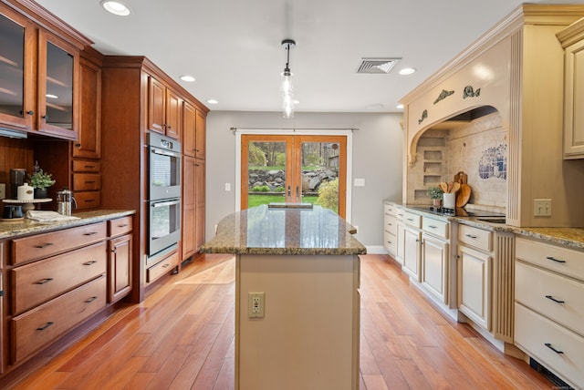 kitchen with double oven, french doors, a center island, backsplash, and visible vents