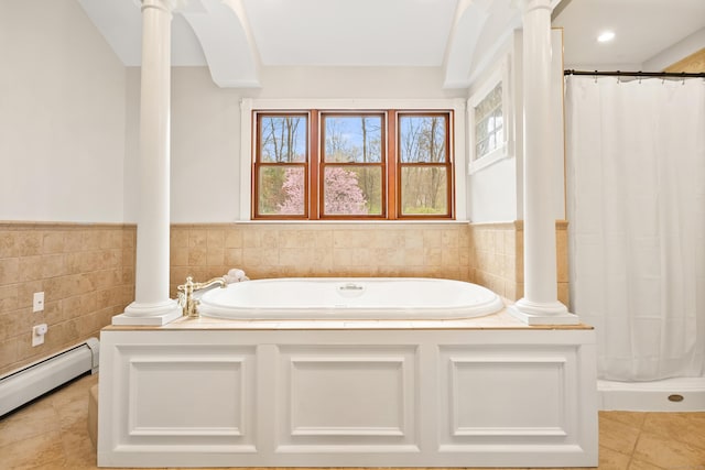 bathroom with wainscoting, tile walls, decorative columns, a baseboard heating unit, and a garden tub
