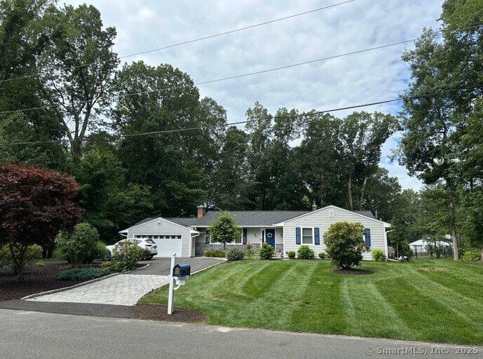 view of front facade featuring a front lawn, an attached garage, and driveway