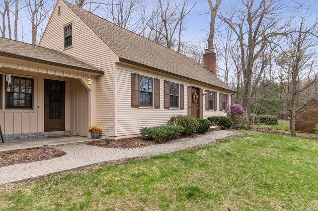 17 Fernwood Ln, Somers, CT 06071 - view of front of home with roof with shingles, a chimney, board and batten siding, and a front lawn