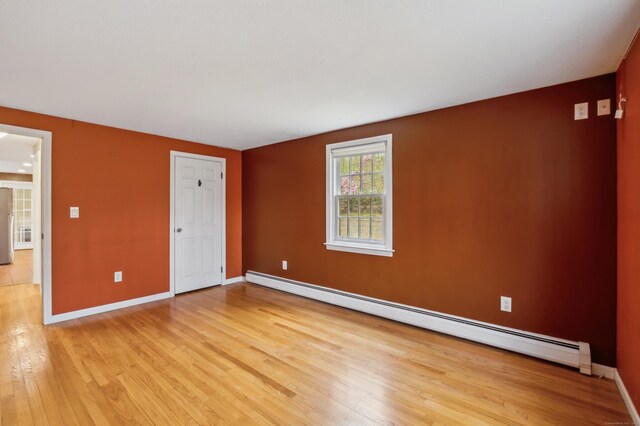 17 Fernwood Ln, Somers, CT 06071 - unfurnished bedroom with baseboards, fridge, light wood-style flooring, and a baseboard radiator