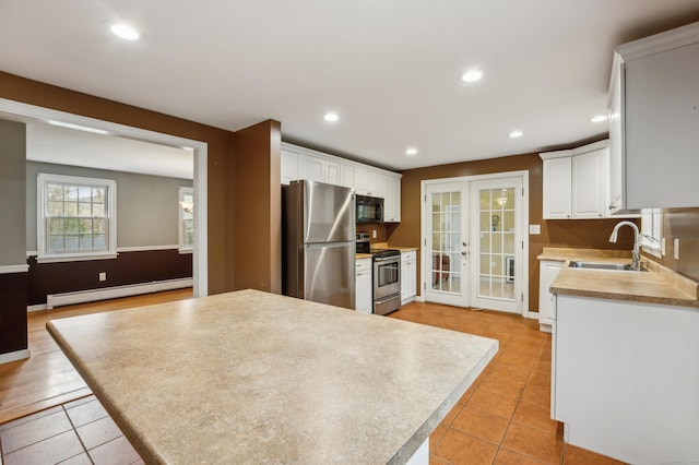 17 Fernwood Ln, Somers, CT 06071 - kitchen with a baseboard radiator, appliances with stainless steel finishes, a sink, white cabinetry, and light tile patterned flooring