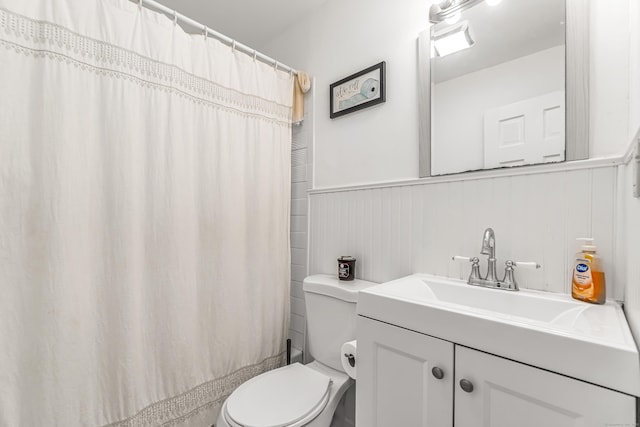 full bath featuring vanity, wainscoting, and toilet