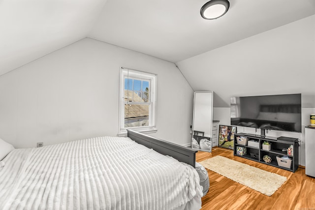 bedroom with wood finished floors and lofted ceiling
