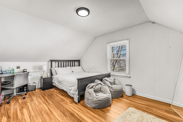 bedroom with light wood-style floors, baseboards, and vaulted ceiling