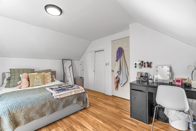 bedroom featuring a closet, light wood finished floors, and vaulted ceiling