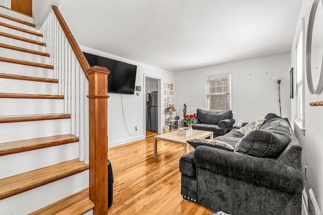 living area with stairs, light wood-style flooring, and visible vents