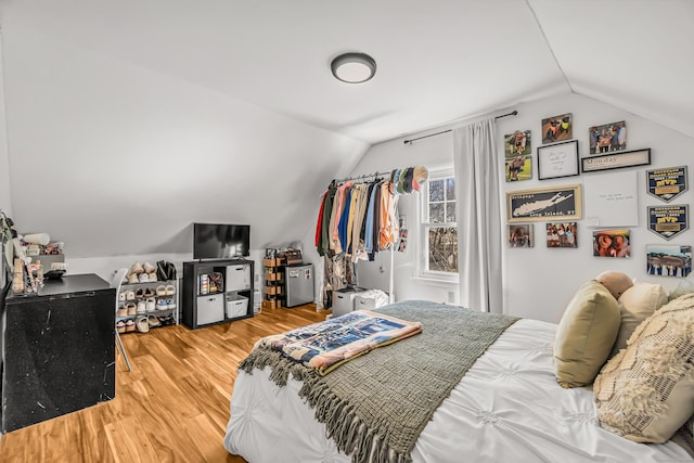 bedroom with wood finished floors and lofted ceiling