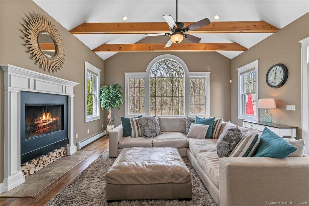 living room with baseboard heating, wood finished floors, a ceiling fan, and vaulted ceiling with beams