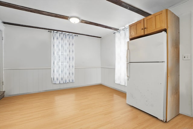 unfurnished room with light wood-style flooring and a wainscoted wall