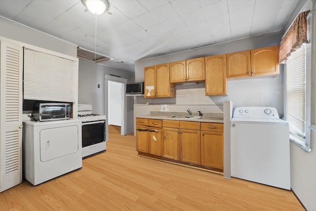 kitchen with washer / dryer, white gas stove, a sink, and stainless steel microwave