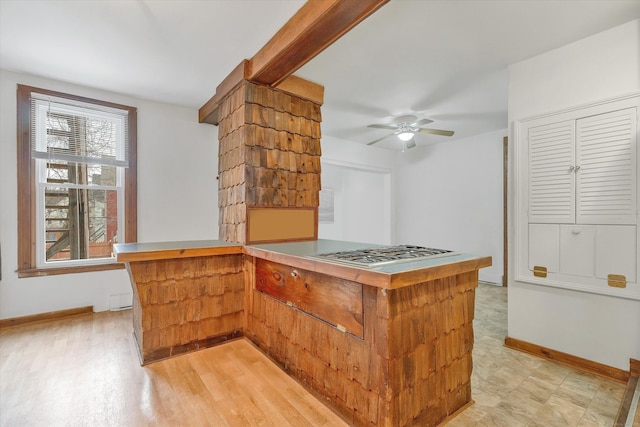 kitchen featuring a ceiling fan, stainless steel gas cooktop, and baseboards