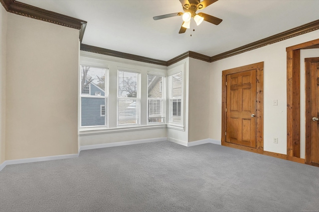 empty room with ornamental molding, a ceiling fan, carpet floors, and baseboards