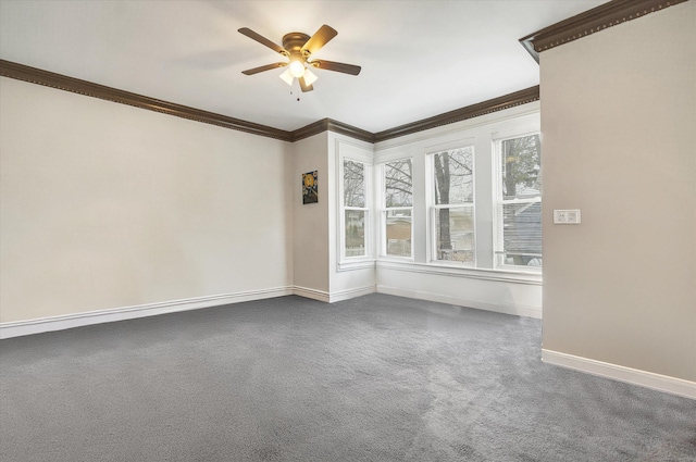 spare room with dark colored carpet, crown molding, a ceiling fan, and baseboards