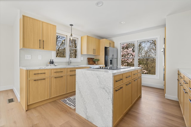 kitchen featuring a center island, stainless steel refrigerator with ice dispenser, light wood-style flooring, and a sink